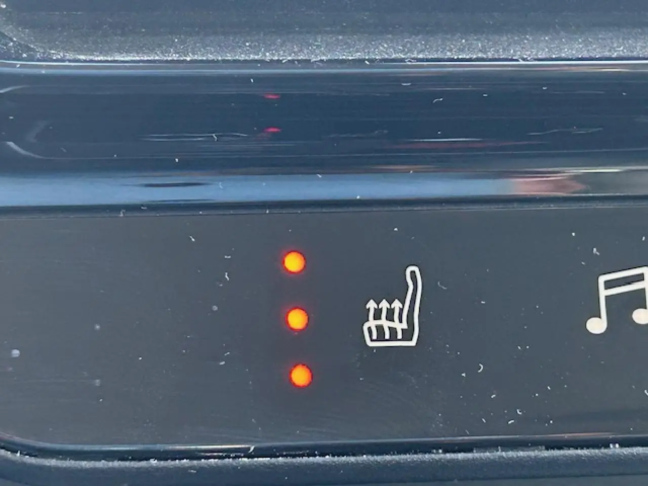 Gros plan sur le bouton de chauffage de siège avec trois voyants rouges allumés dans un Citroën C5 Aircross gris platinium.