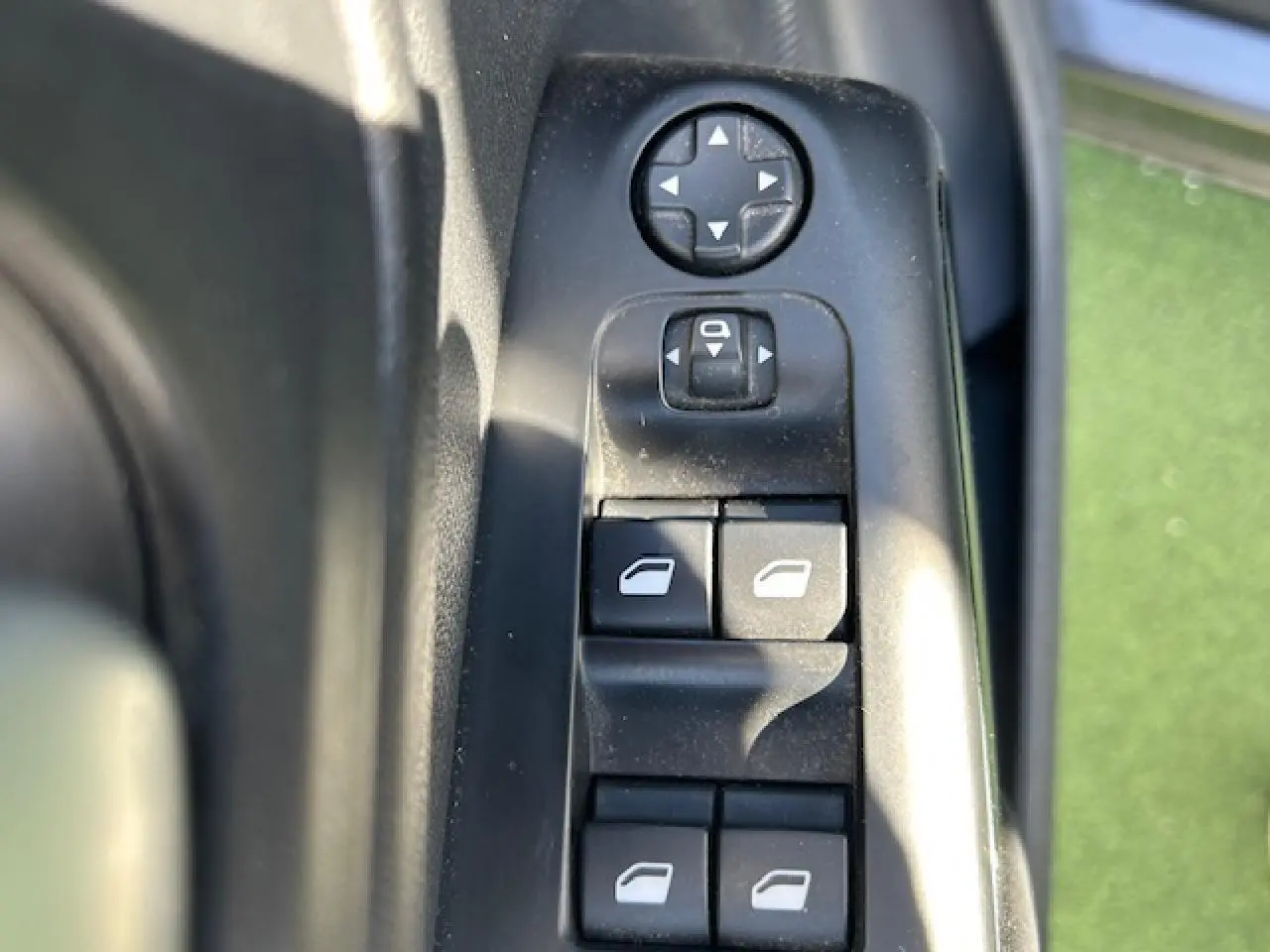 Gros plan sur les commandes des vitres électriques côté conducteur du Citroën C5 Aircross gris platinium, avec réglage des rétroviseurs.