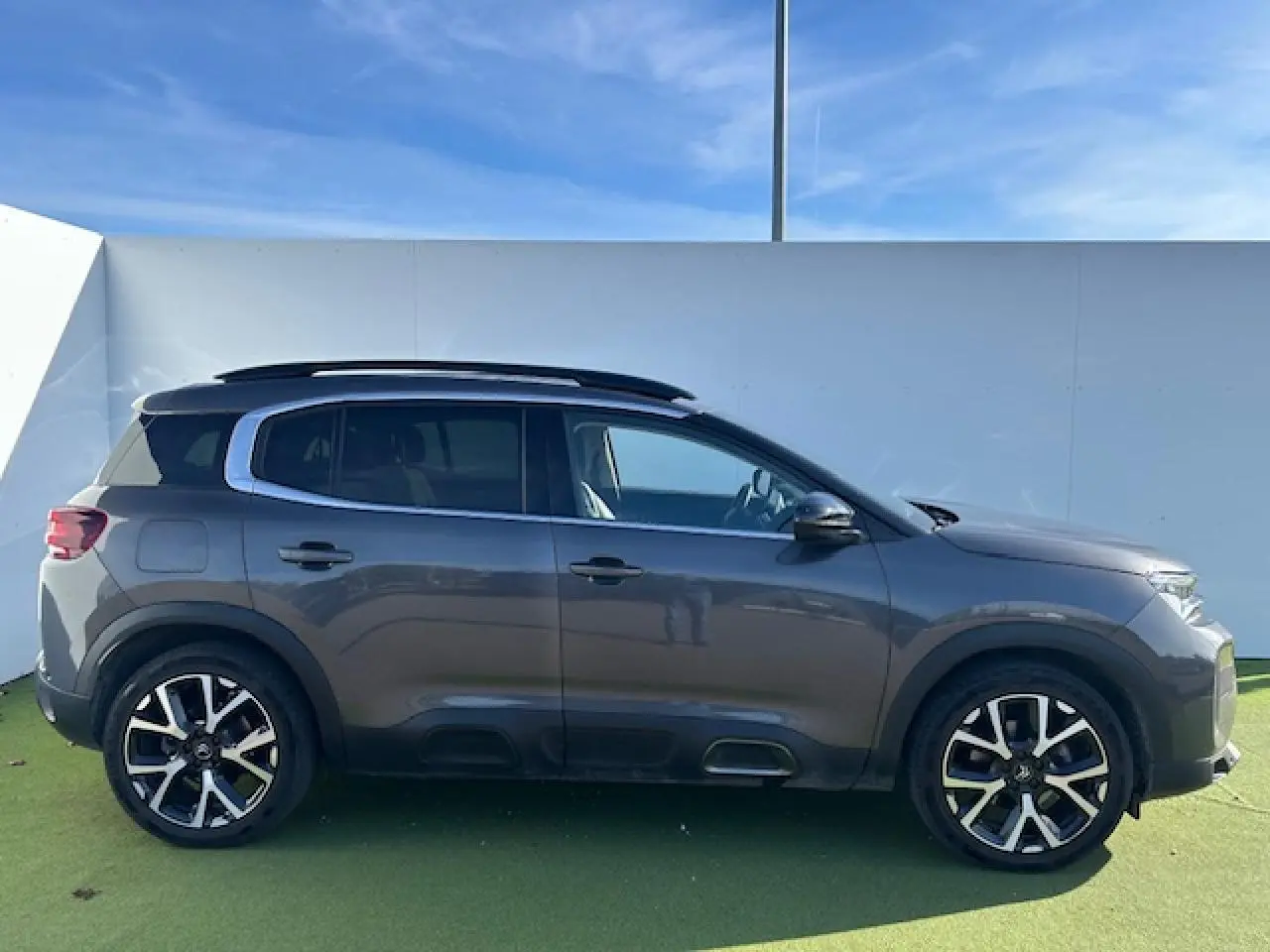 Profil droit d'un Citroën C5 Aircross gris platinium 2022 avec barres de toit et jantes alliage noires et argentées.