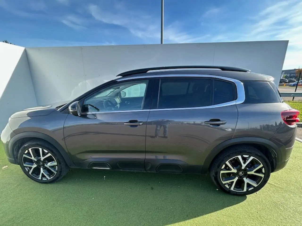 Profil côté gauche du SUV Citroën C5 Aircross gris platinium 2022 avec jantes alliage et barres de toit noires.