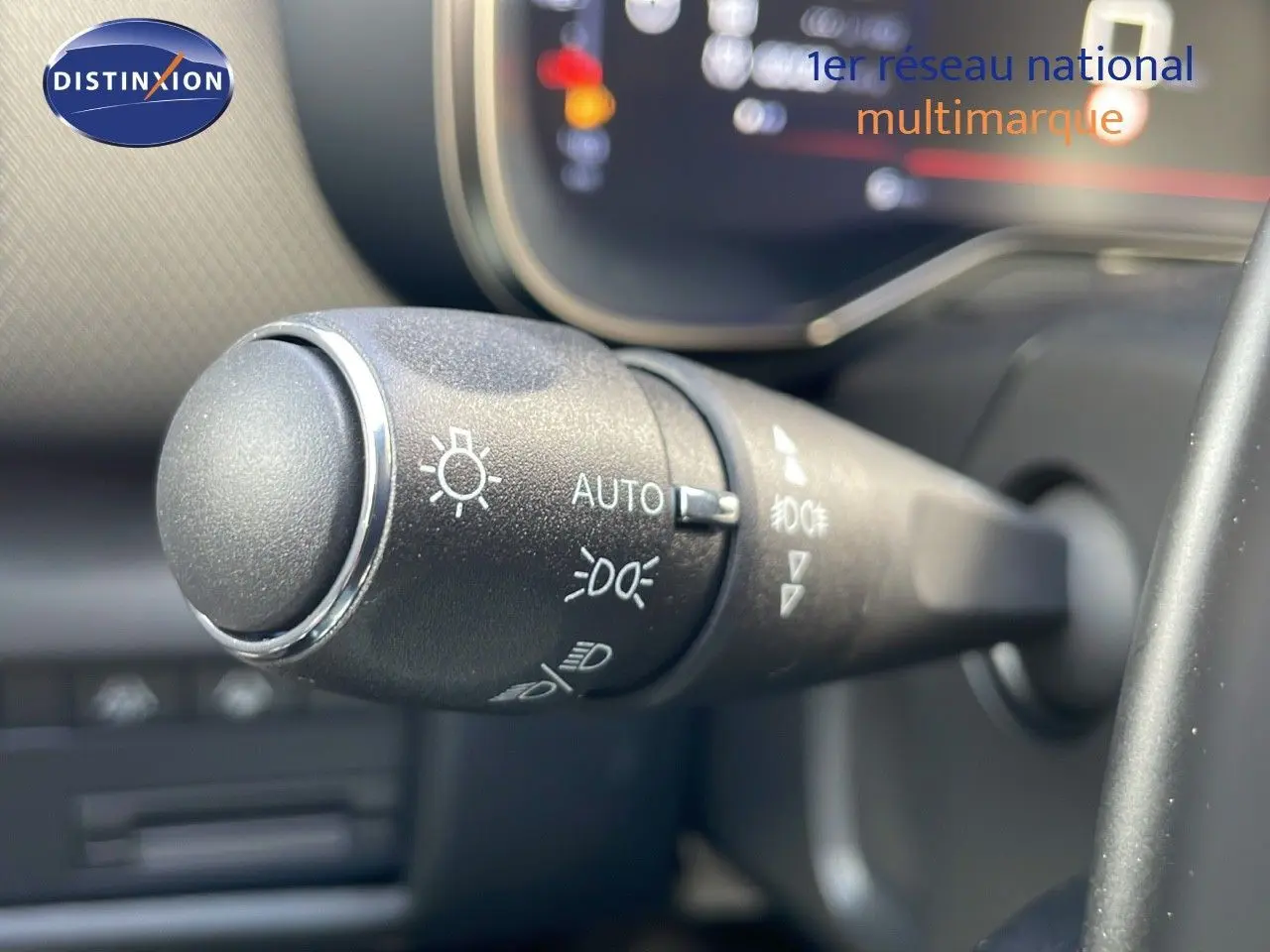 Gros plan sur la commande des phares du Citroën C5 Aircross 2025, intérieur noir avec affichage numérique flou.