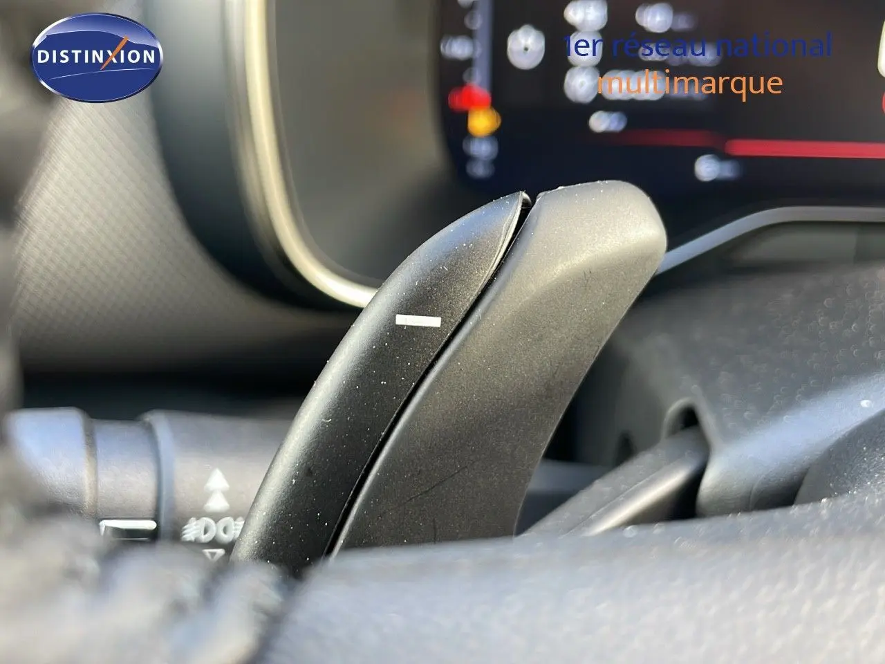 Gros plan sur la palette de changement de vitesse au volant d'une Citroën C5 Aircross bleu Eclipse Métal, tableau de bord flou en arrière-plan.