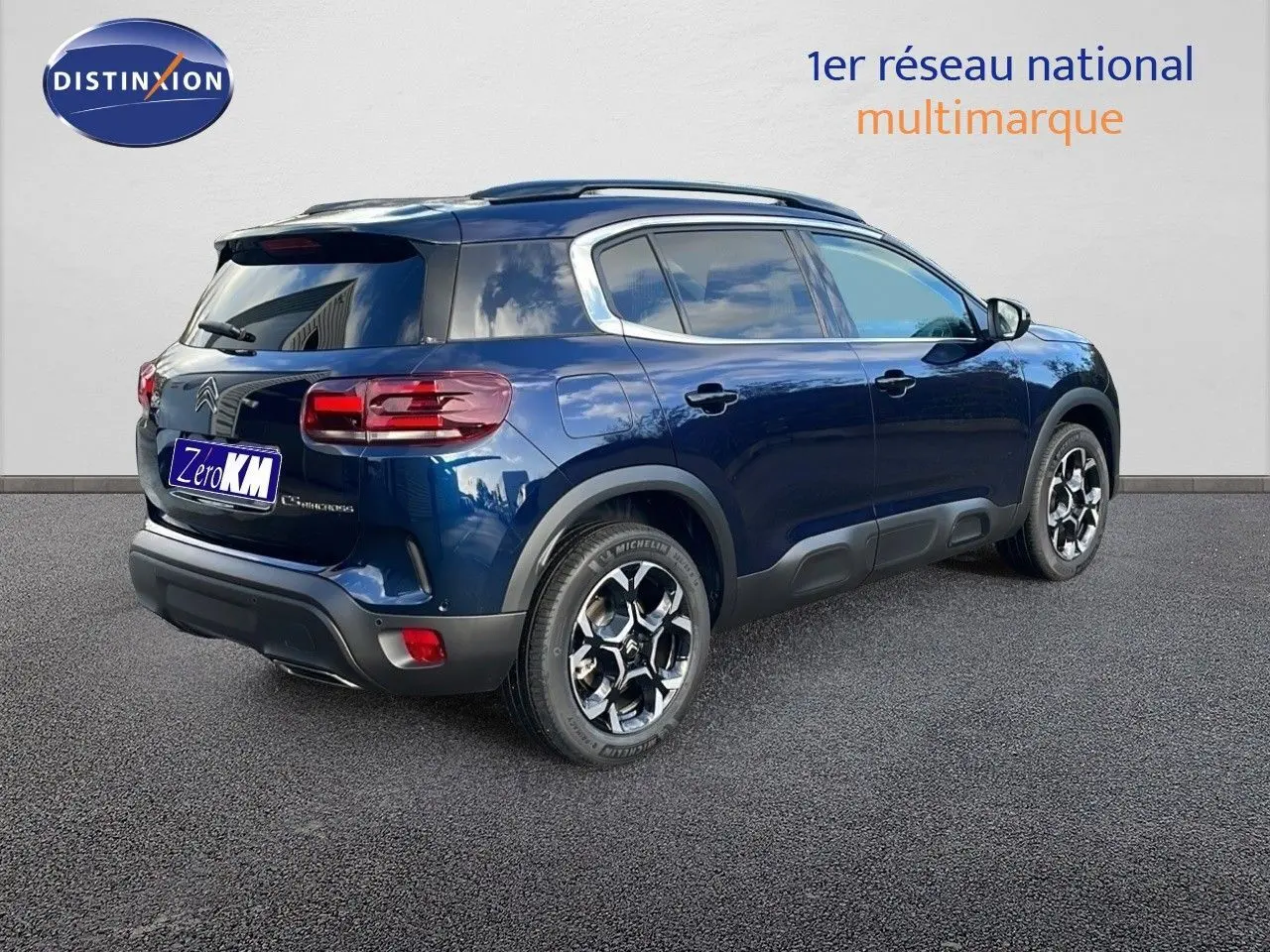 Vue 3/4 arrière droite d'un Citroën C5 Aircross bleu Eclipse Metal avec jantes alliage et barres de toit.
