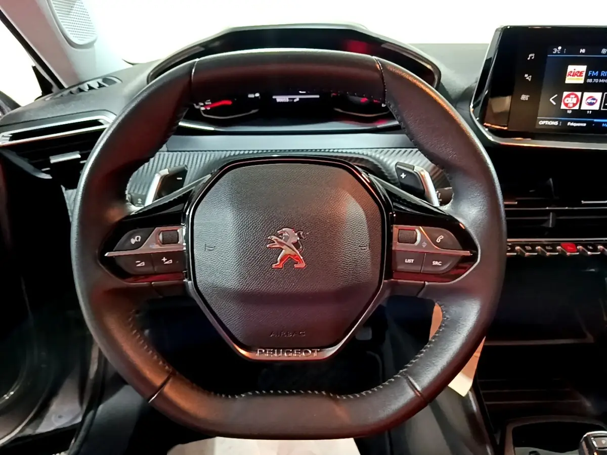 Vue rapprochée du volant cuir multifonctions noir du Peugeot 2008 2021 avec tableau de bord et écran tactile visibles.