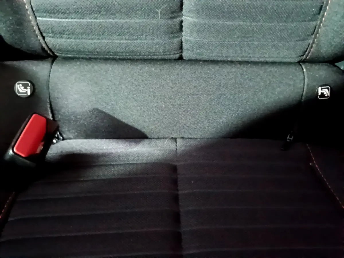 Gros plan sur la banquette arrière noire du Peugeot 2008, montrant les fixations Isofix et la ceinture rouge.