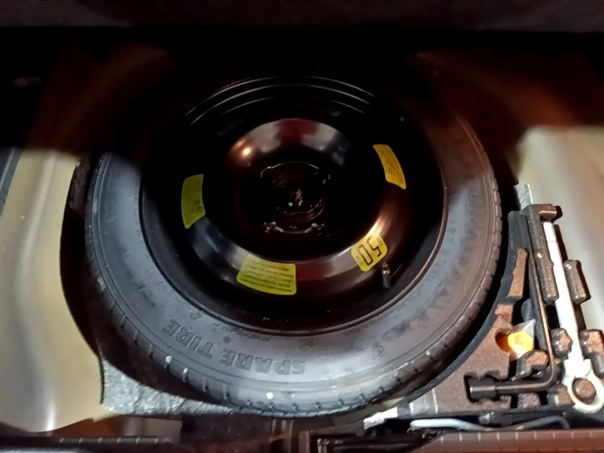 Vue rapprochée de la roue de secours noire dans le coffre d'une Peugeot 2008 gris clair de 2021.