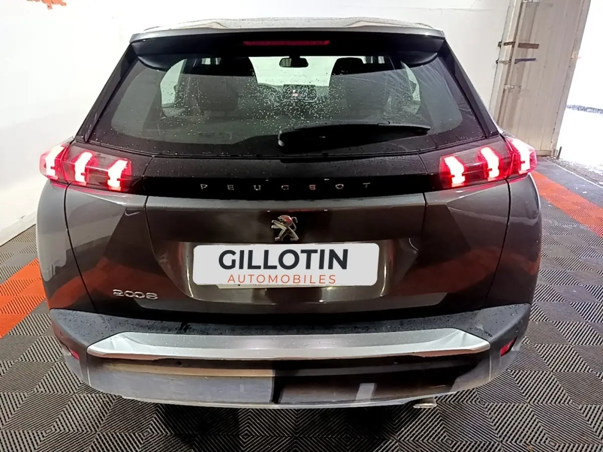 Vue arrière d’un Peugeot 2008 gris clair avec feux arrière LED allumés dans un garage.
