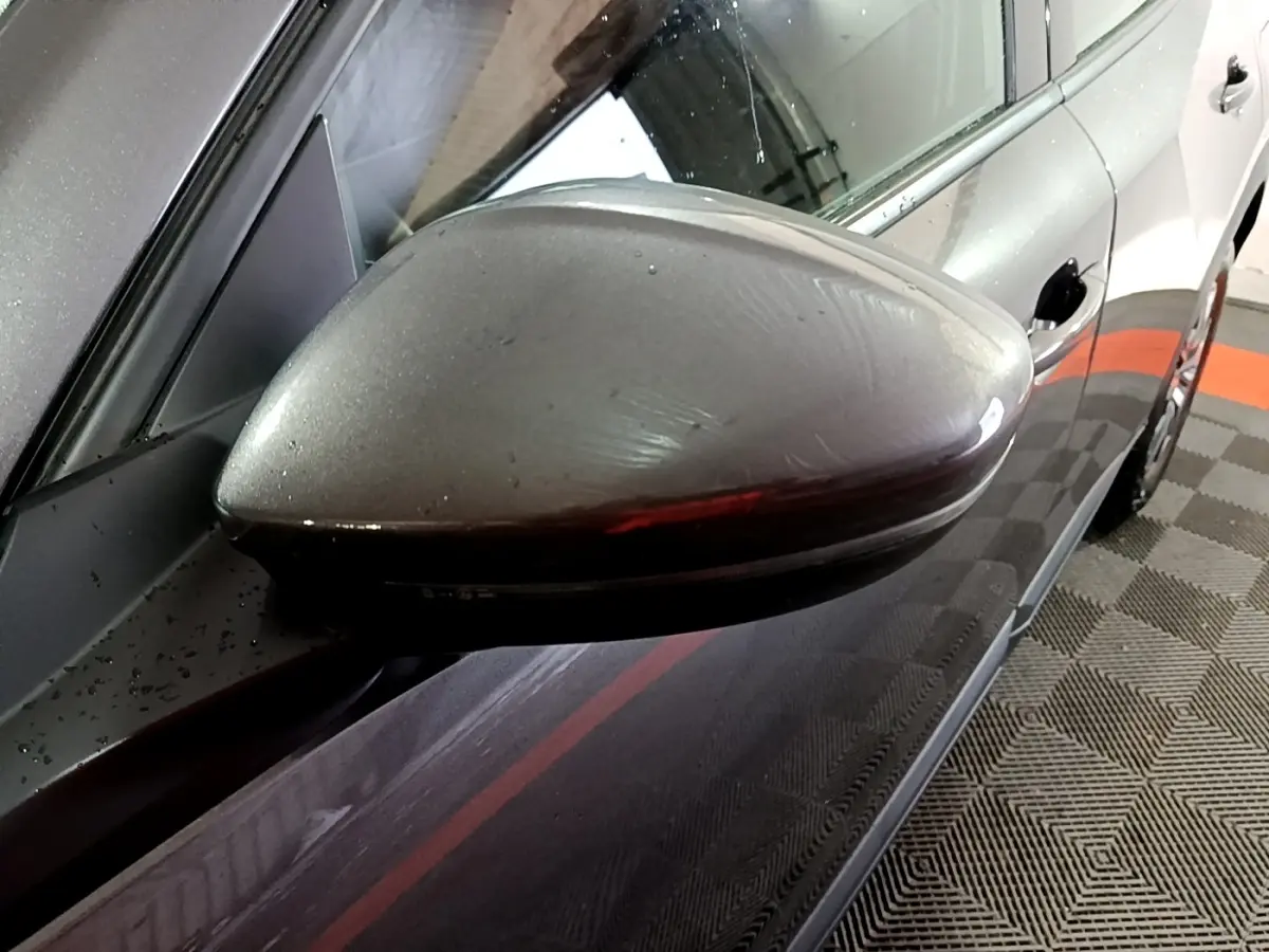 Gros plan sur le rétroviseur côté gauche gris clair du Peugeot 2008, avec reflet de l'environnement intérieur.