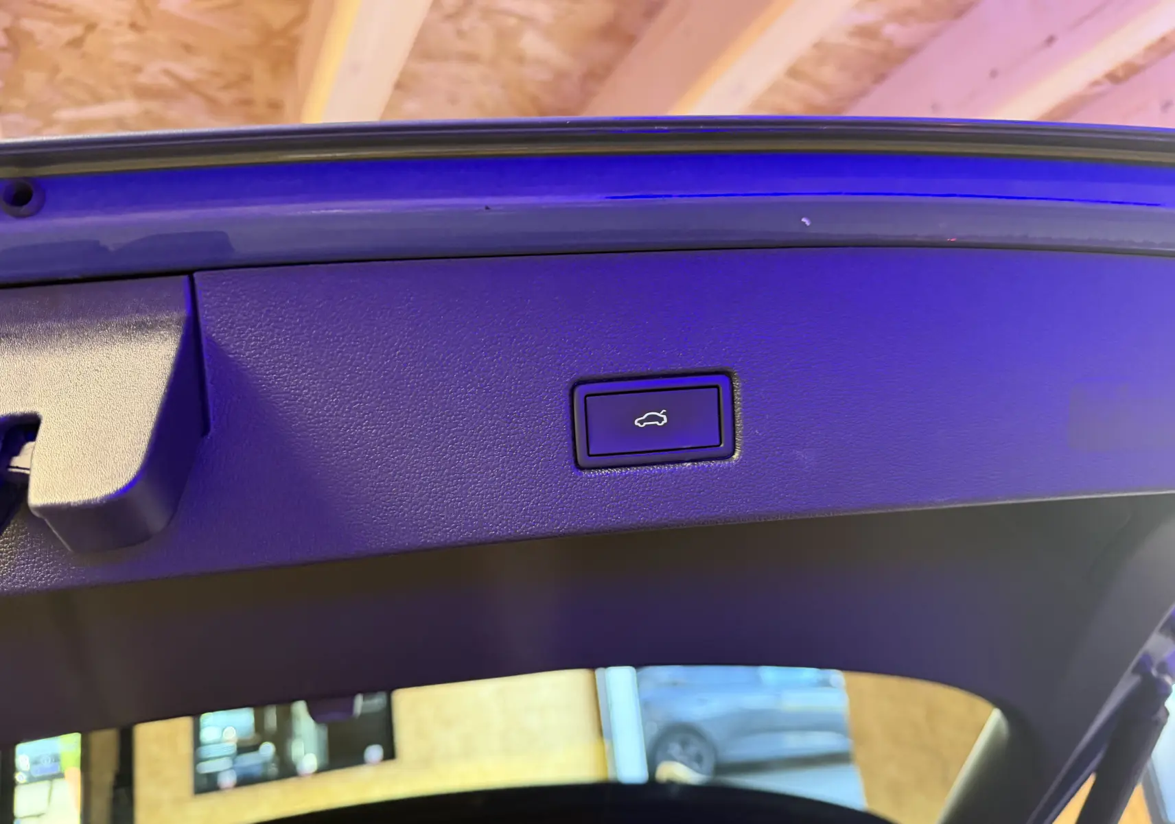 Bouton d'ouverture électrique du hayon sur la partie intérieure du coffre d'un Volkswagen T-Roc bleu 2022.