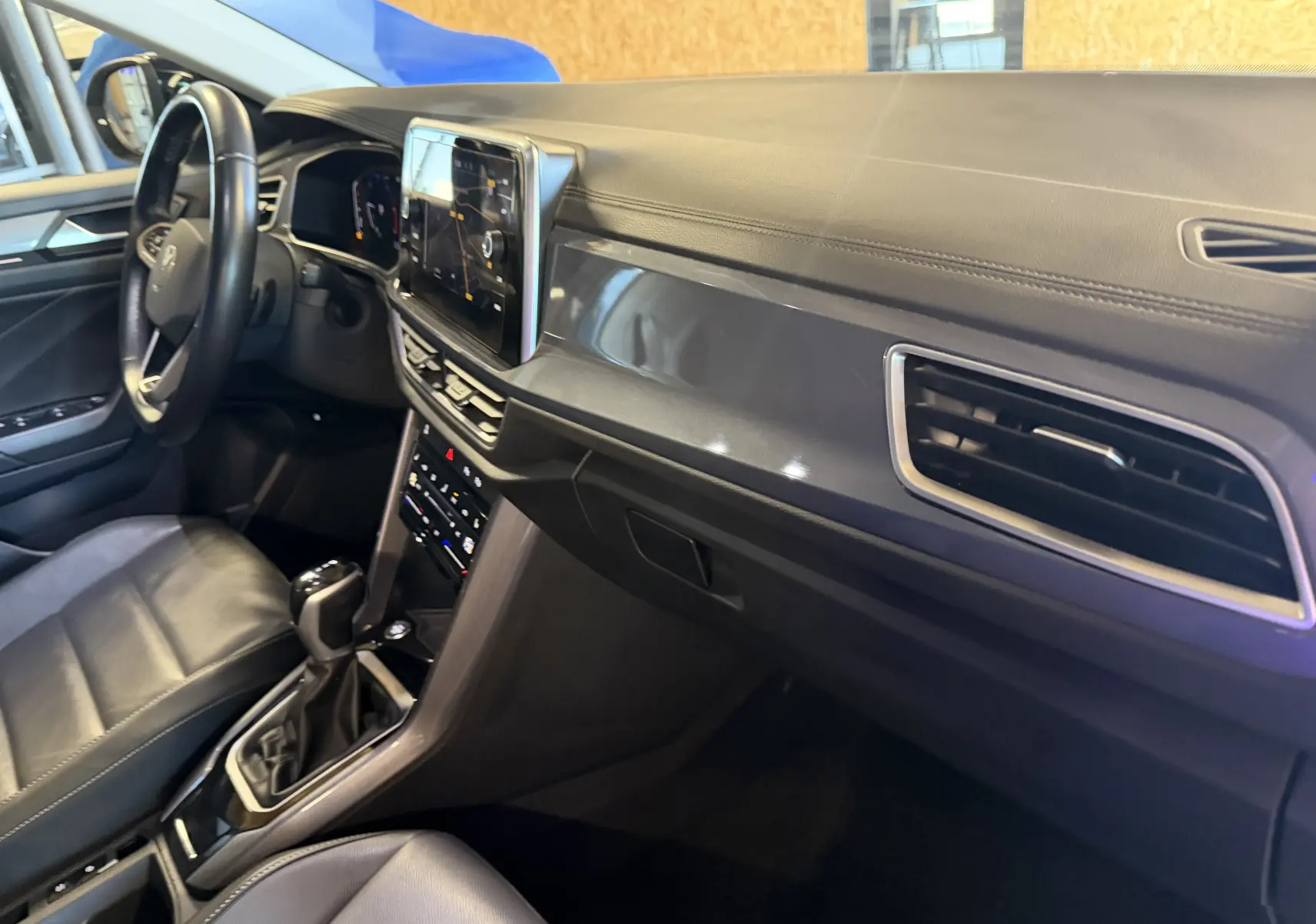 Vue intérieure côté conducteur du Volkswagen T-Roc 2.0 TDI 150 DSG7, tableau de bord noir avec écran tactile central.