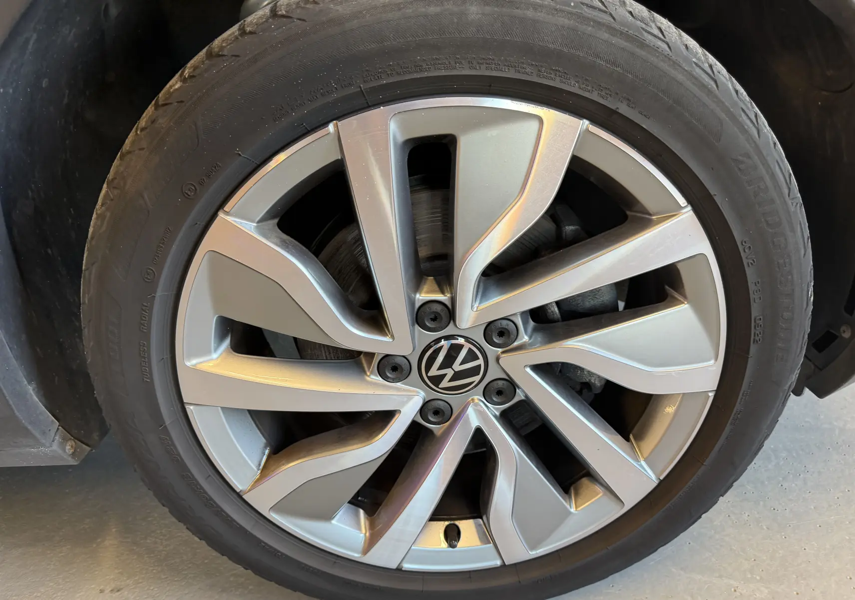 Gros plan sur la jante alliage argentée au design moderne du Volkswagen T-Roc bleu, roue avant droite visible.