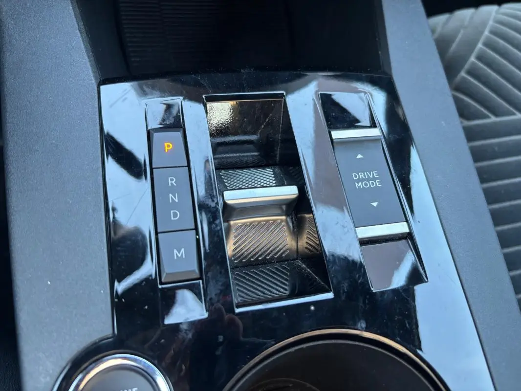 Gros plan sur la console centrale noire brillante de la Lancia Ypsilon 2025, montrant la sélection de boîte auto et le bouton Drive Mode.
