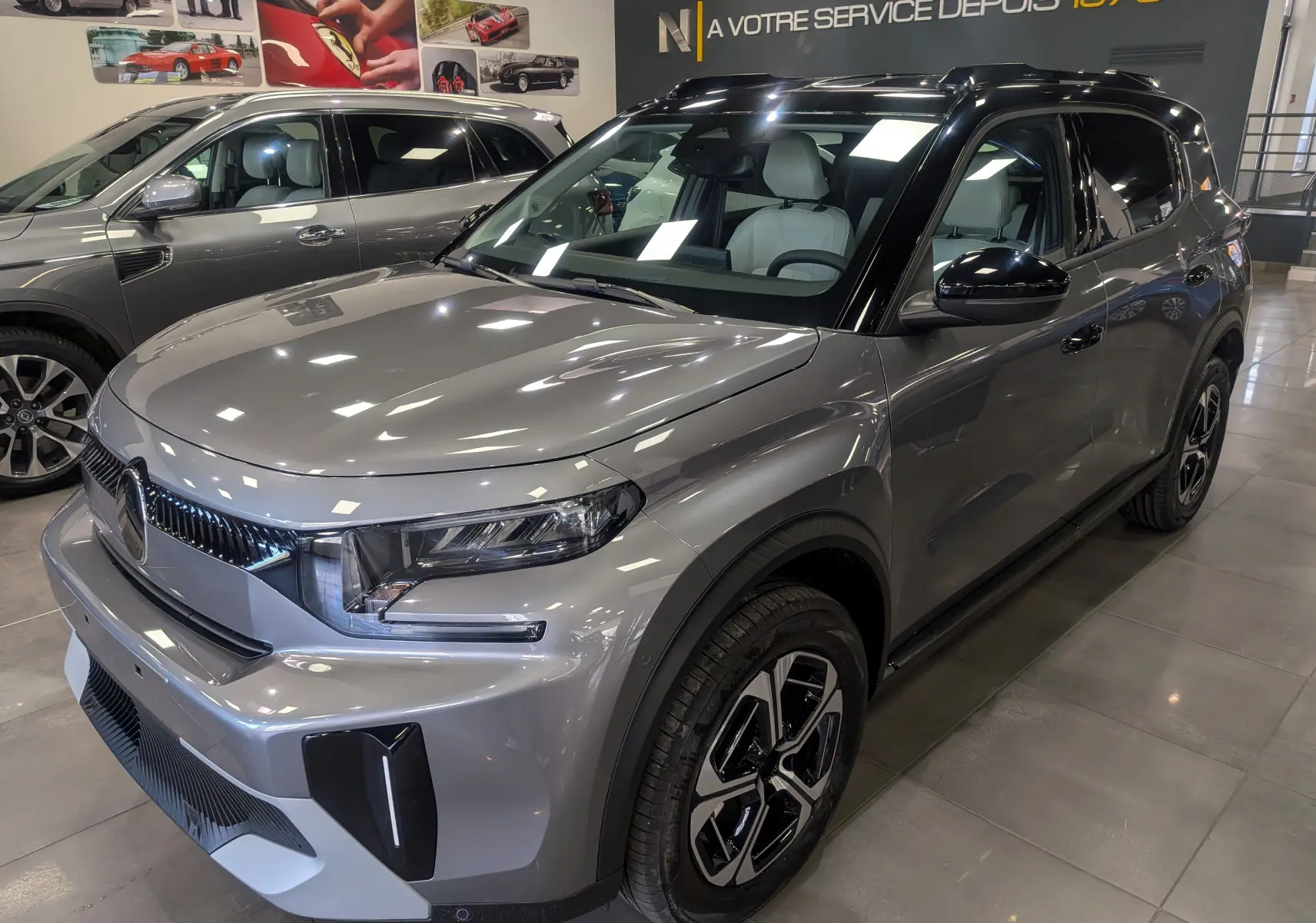 Vue 3/4 avant droite d'un Citroën C3 Aircross hybride 2026 gris Mercury avec toit noir et jantes bi-ton.