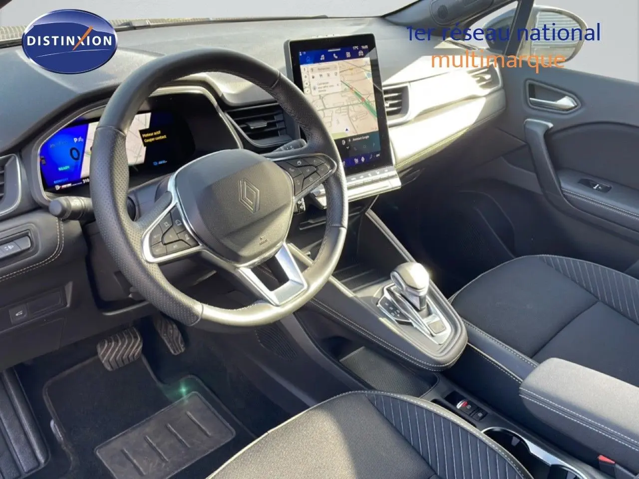 Intérieur Renault Symbioz 2025 vu côté conducteur, volant cuir, écran tactile vertical et sièges tissu noir avec surpiqûres grises.
