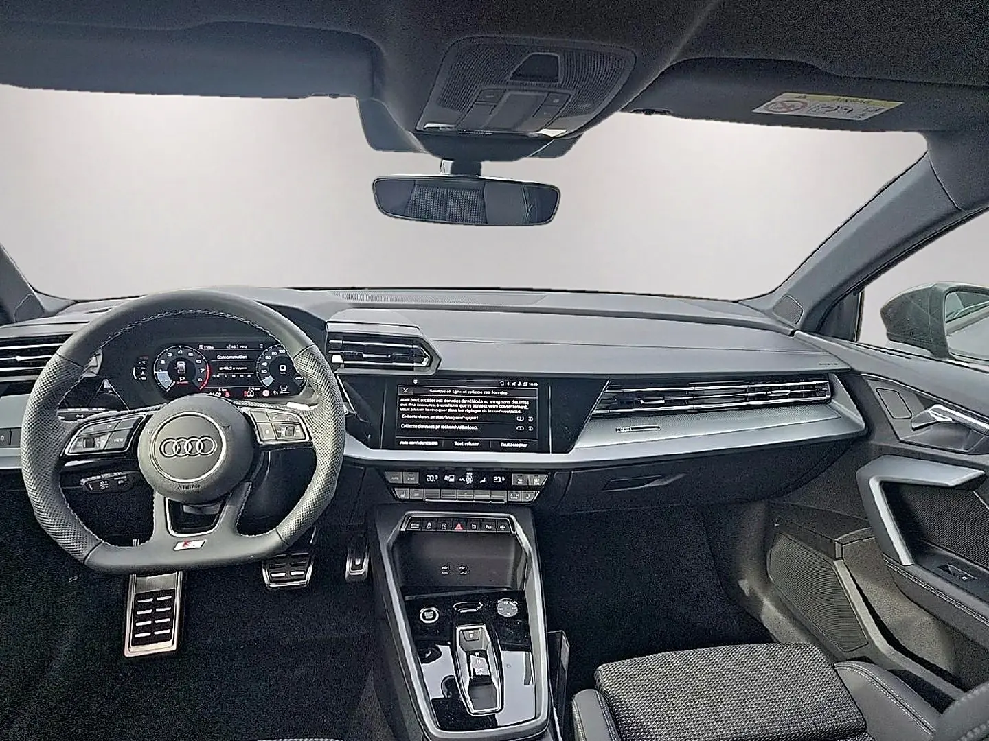 Vue avant intérieure de l'Audi A3 Sportback 2026, tableau de bord noir avec volant sport multifonction et écran central tactile.