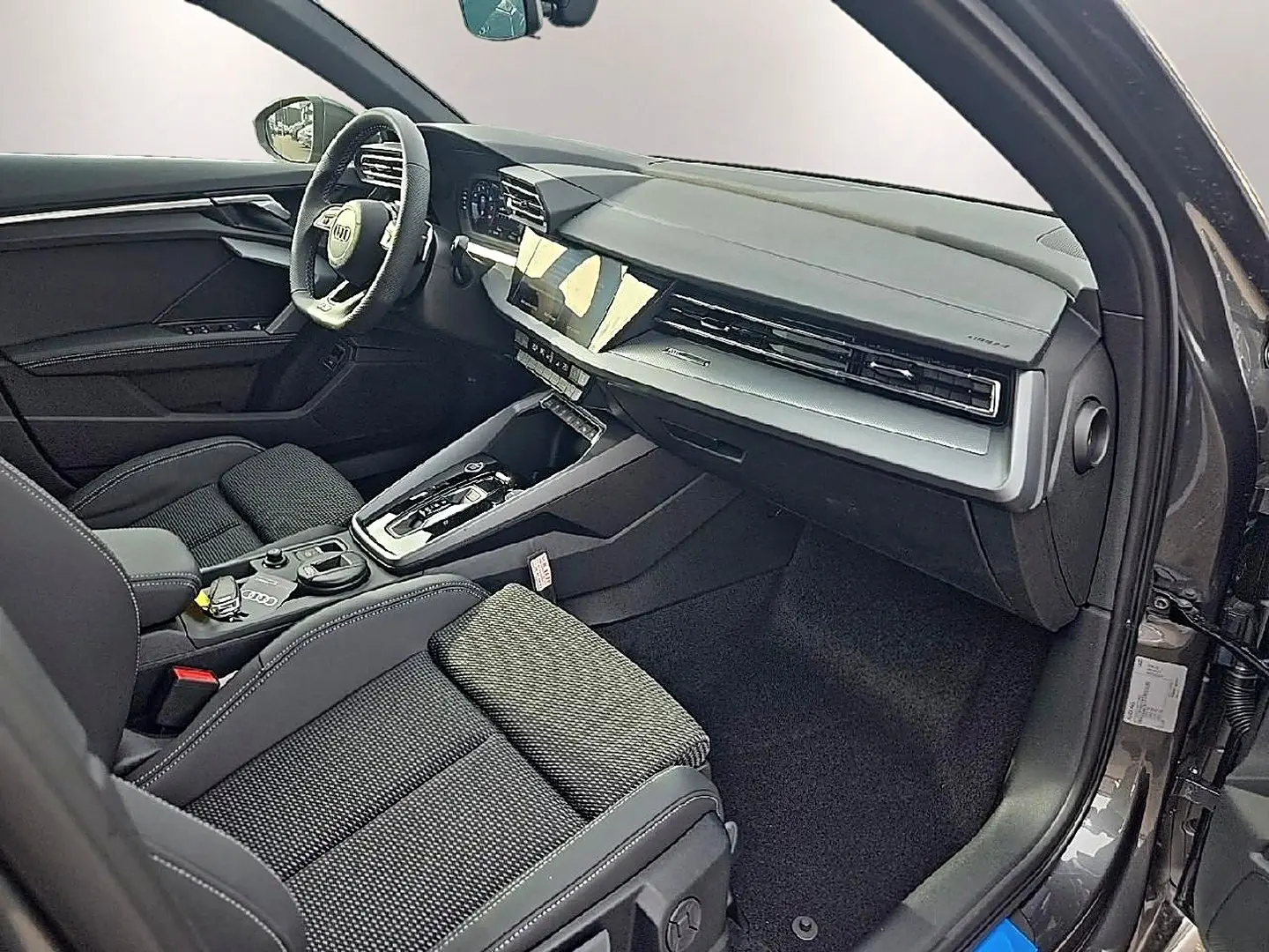 Intérieur avant droit d’Audi A3 Sportback gris Daytona, avec tableau de bord moderne et sièges sport noirs.