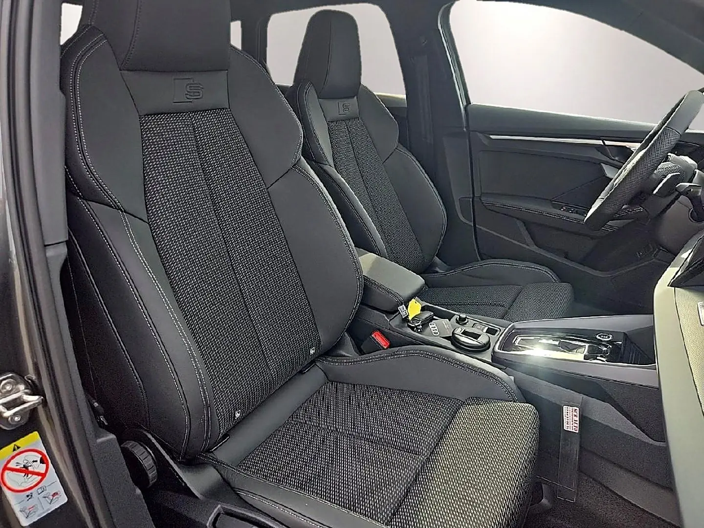 Vue intérieure côté gauche des sièges sport noirs avec surpiqûres blanches et logo S sur un Audi A3 Sportback 2026.