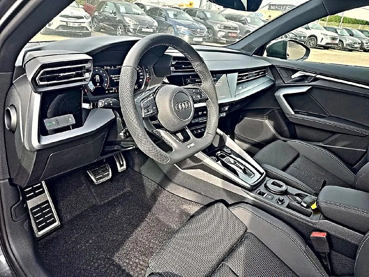 Vue intérieure côté conducteur de l'Audi A3 Sportback 2026, volant sport cuir et console centrale moderne noire.