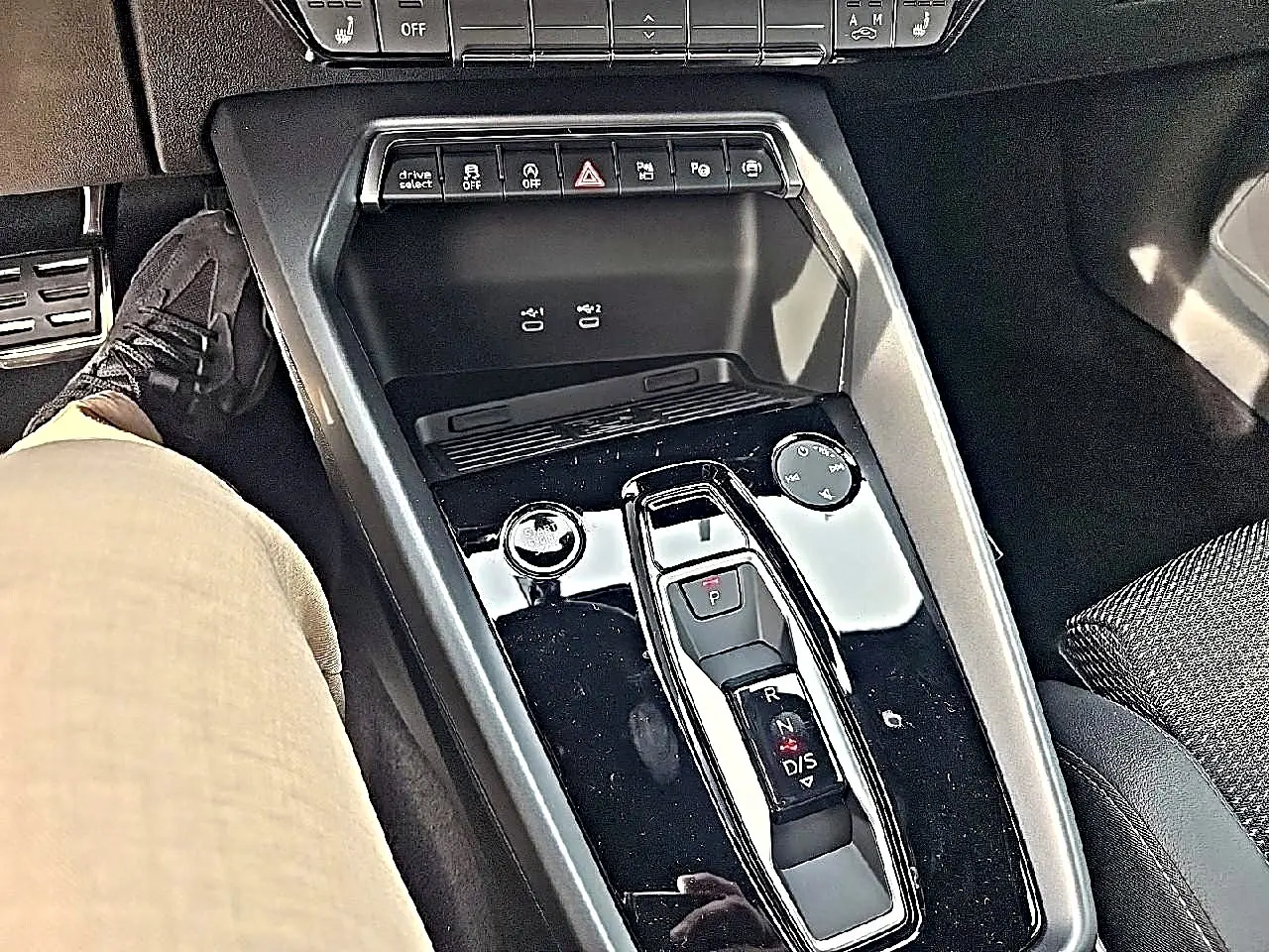 Vue plongeante sur la console centrale noire brillante de l'Audi A3 Sportback 1.5 TFSI 150 hybride, avec levier de vitesses automatique.