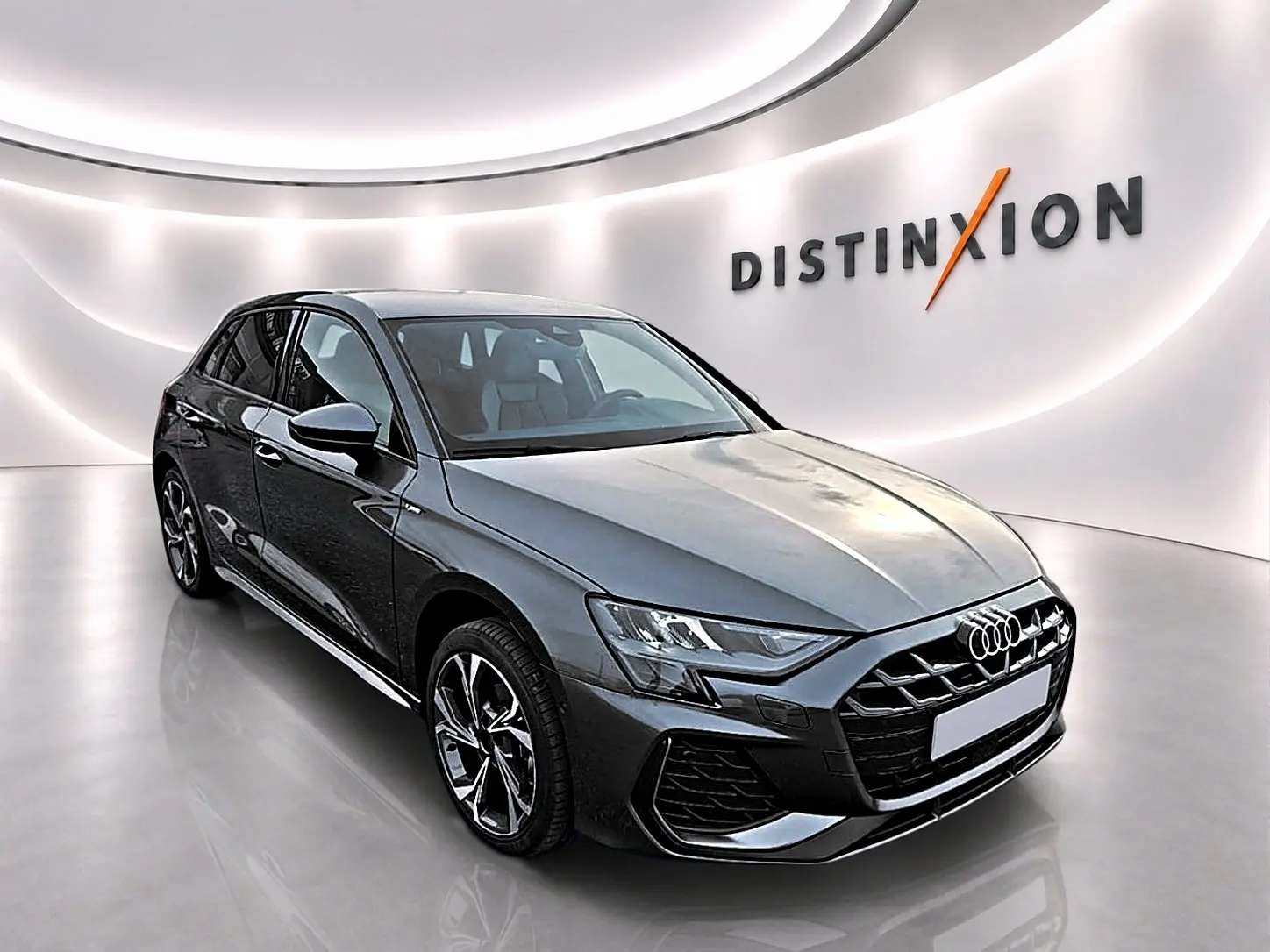 Audi A3 Sportback gris Daytona vue 3/4 avant droit, avec jantes alu et calandre noire distinctive.