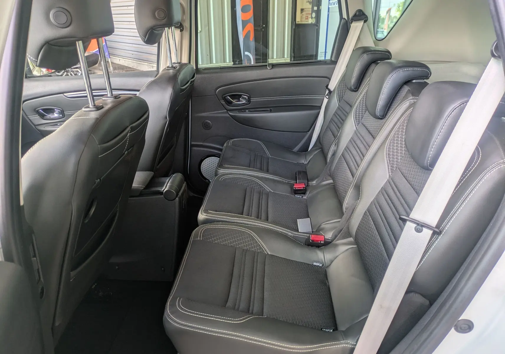 Vue intérieure côté droit des sièges arrière en cuir noir avec surpiqûres blanches du Renault Scenic IV blanc.