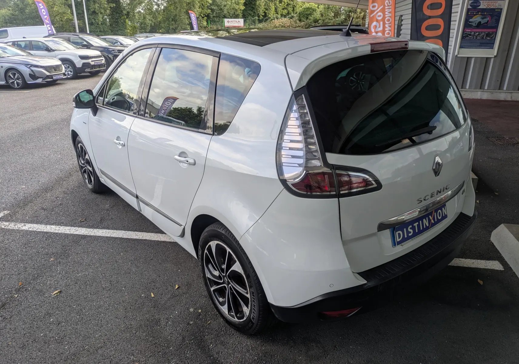 Renault Scénic IV blanc vue 3/4 arrière droit, avec jantes alliage noires et toit panoramique noir.
