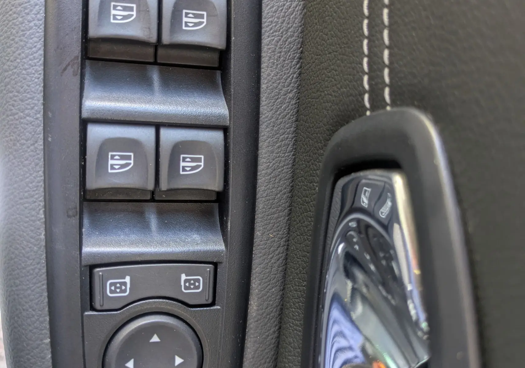 Détail des commandes de lève-vitres et réglage des rétroviseurs côté conducteur du Renault Scenic IV blanc de 2015.