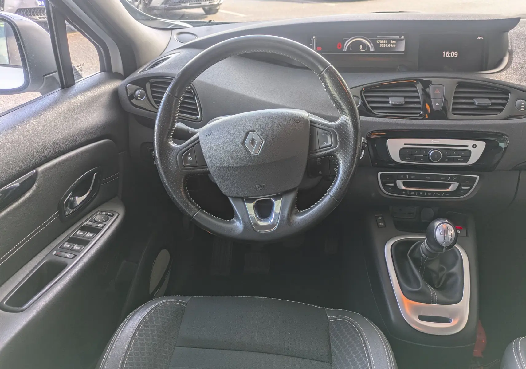 Vue intérieure centrée sur le volant et la console centrale d’un Renault Scenic IV diesel blanc avec boîte manuelle.