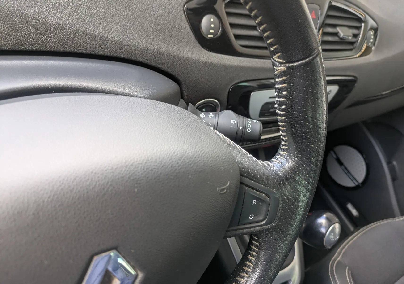 Gros plan sur le volant en cuir noir et la console centrale d’un Renault Scenic IV blanc, version 1.5 DCI 110 Bose.