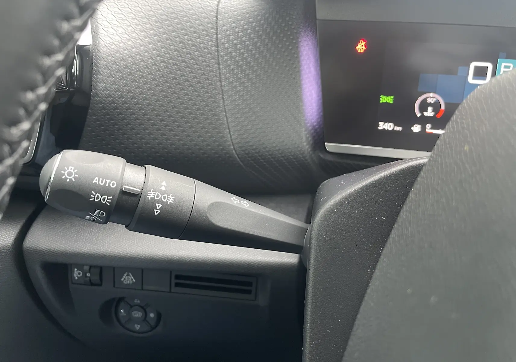 Gros plan sur la commande des feux et clignotants côté gauche du tableau de bord d’une Citroën C4 blanche 2022.