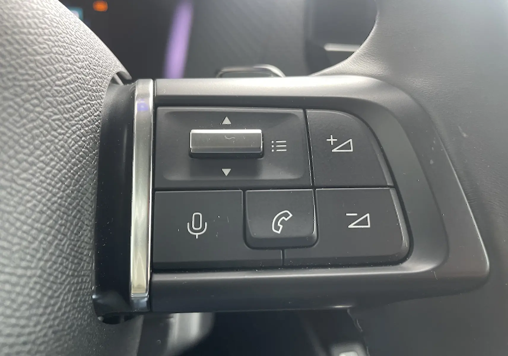 Gros plan sur les commandes au volant côté gauche d'une Citroën C4 blanche, boutons de volume et appel visibles.