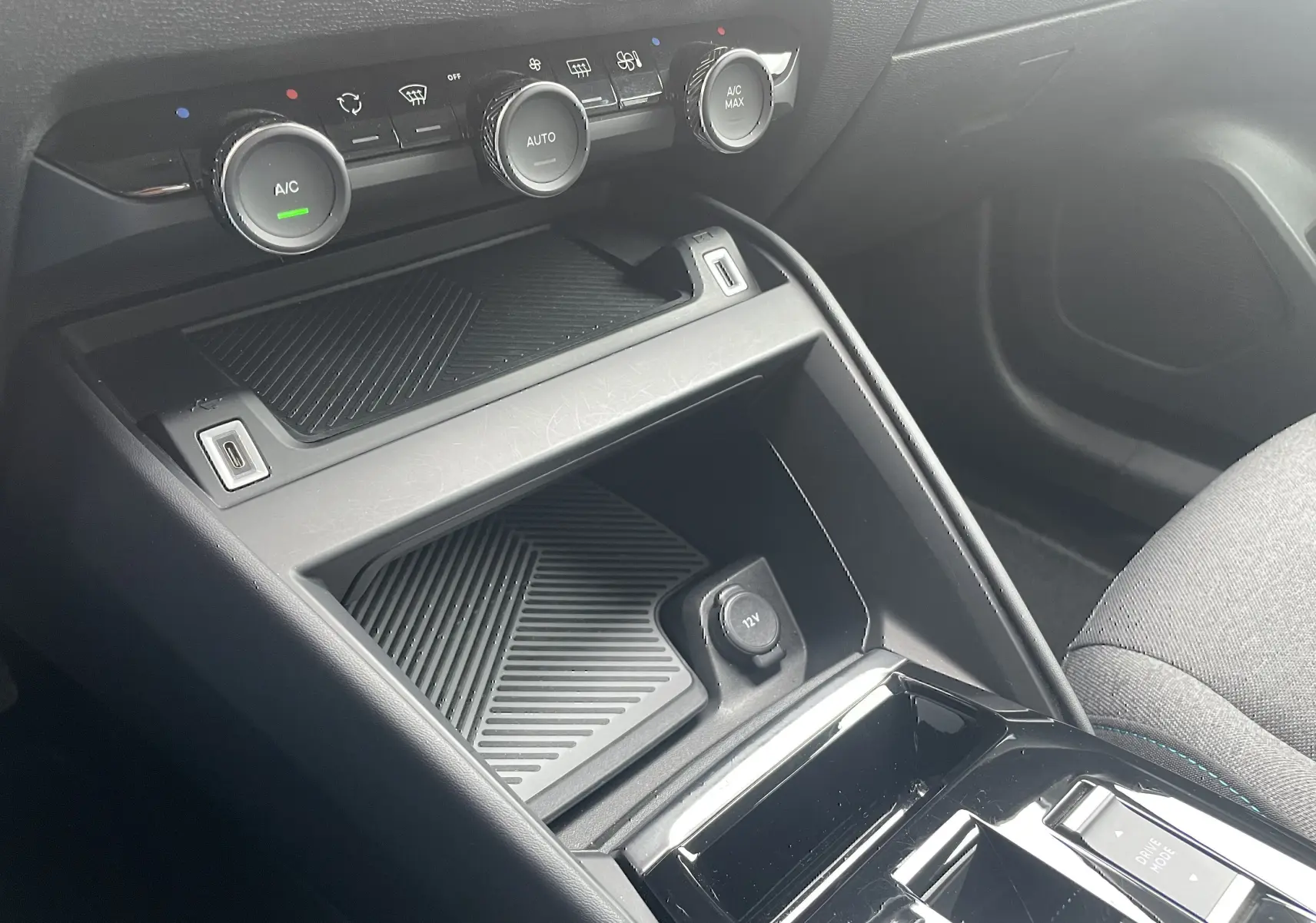 Vue rapprochée de la console centrale noire avec commandes climatisation et prise 12V d'une Citroën C4 blanche 2022.