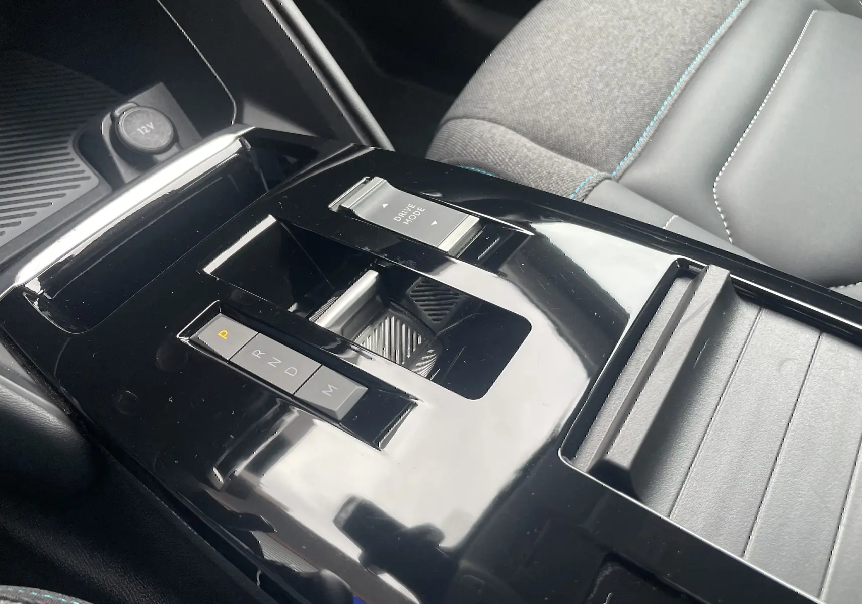 Gros plan sur la console centrale noire brillante de la Citroën C4 2022, avec levier de vitesses automatique et bouton Drive Mode.