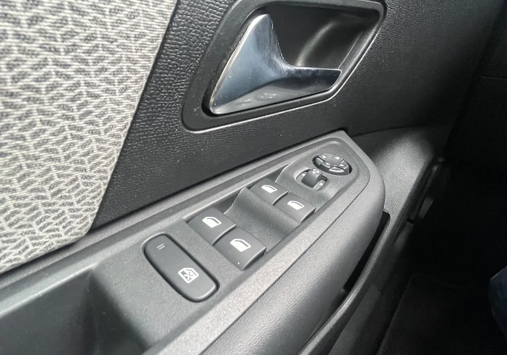 Gros plan sur la commande des vitres et la poignée intérieure côté gauche d’une Citroën C4 blanche de 2022.