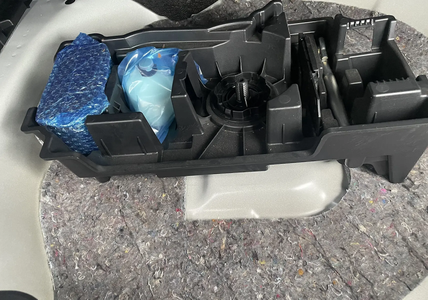 Rangement noir sous le coffre d'une Citroën C4 blanche 2022, contenant des outils et accessoires emballés.