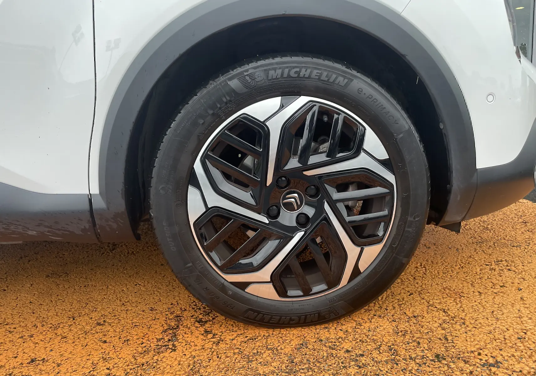 Gros plan sur la roue avant droite blanche d'une Citroën C4 2022, avec jante noire et argentée au design moderne.