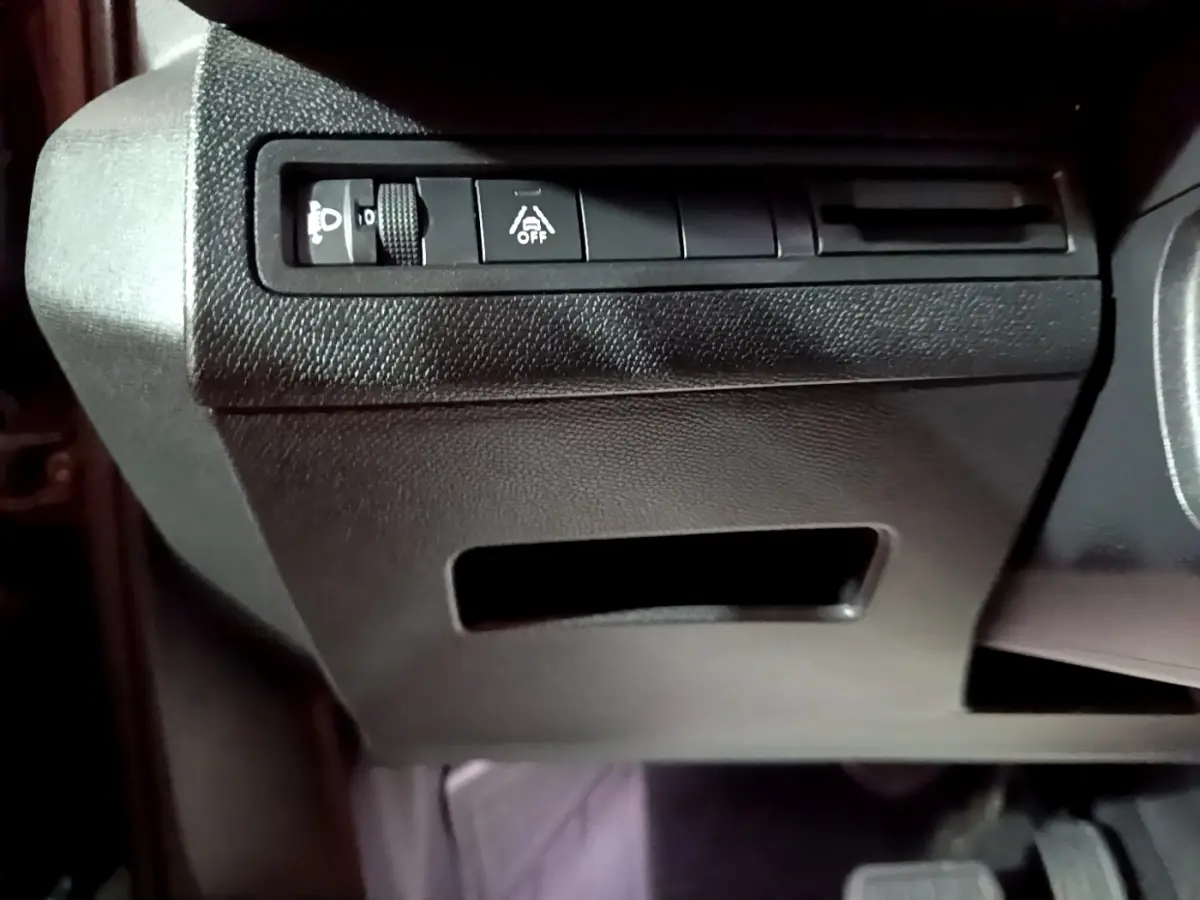 Gros plan sur les commandes d’éclairage et d’aide à la conduite côté gauche du tableau de bord noir du Peugeot 3008 2022.