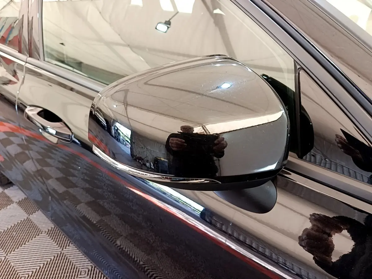 Gros plan sur le rétroviseur côté conducteur noir brillant d’un Volvo V60 D3 Business 2020 avec porte assortie.