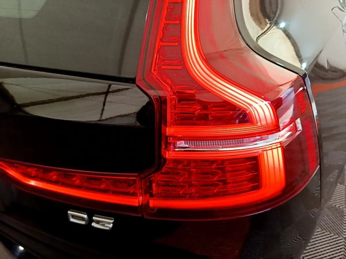 Gros plan sur le feu arrière droit rouge d’une Volvo V60 D3 noire, mettant en valeur le badge D3 et la carrosserie brillante.