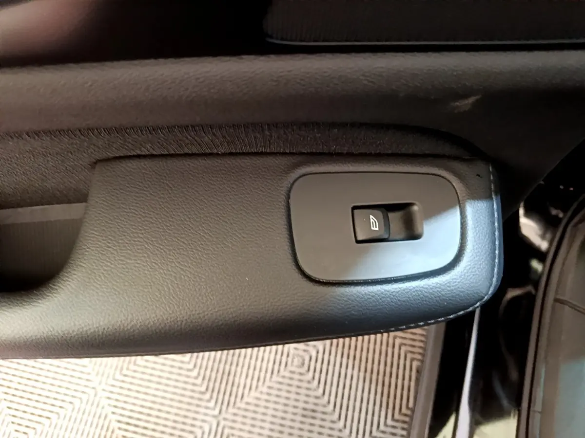 Gros plan sur le bouton de commande de la vitre électrique côté porte intérieure d’une Volvo V60 noire.
