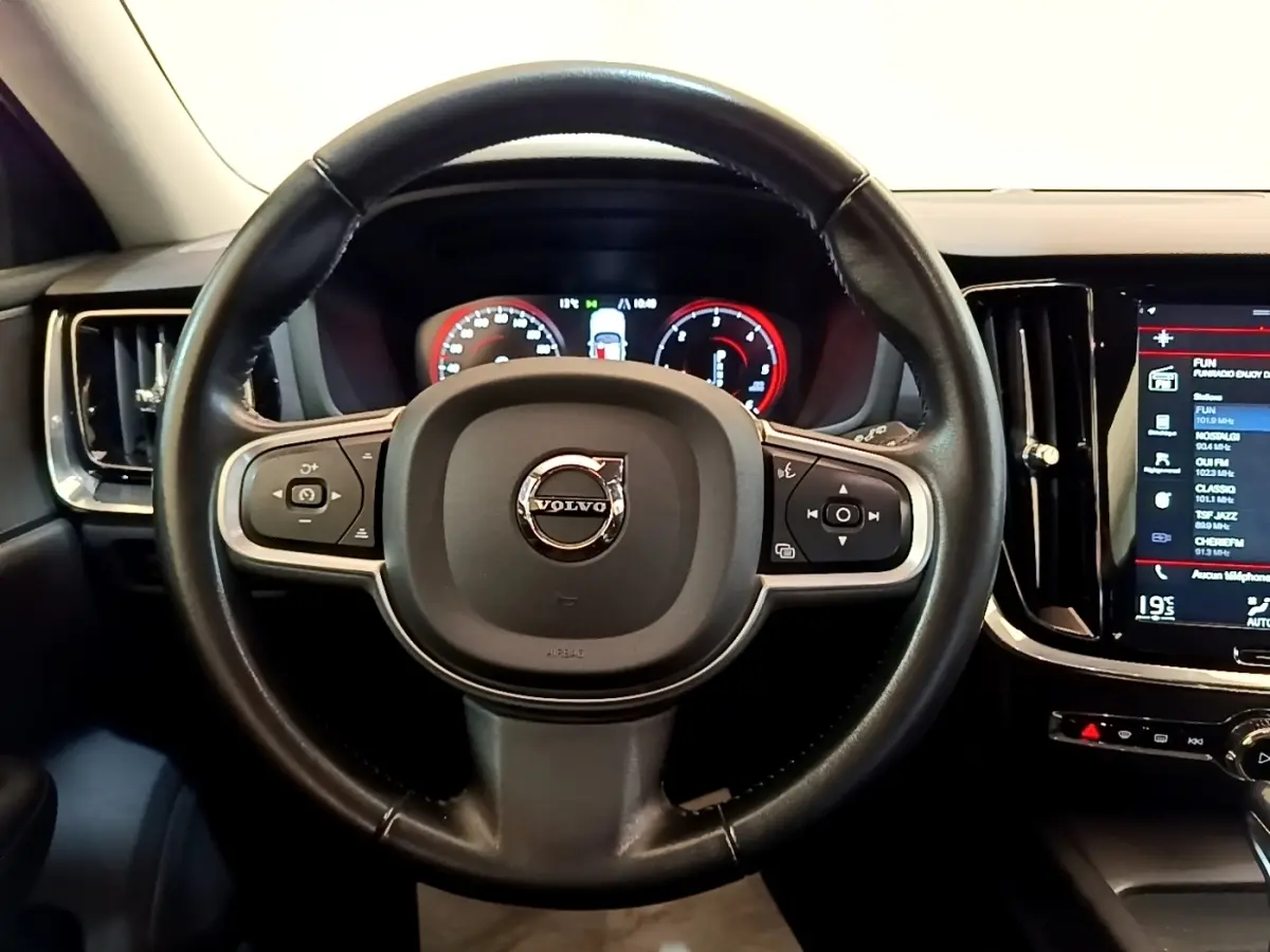 Vue centrée sur le volant en cuir noir de la Volvo V60 2020 avec tableau de bord numérique et écran tactile latéral.