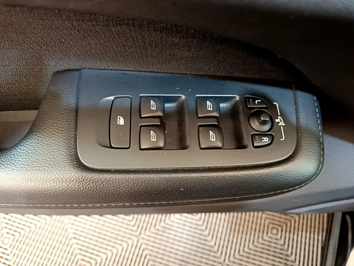 Gros plan sur les commandes de lève-vitres et réglage des rétroviseurs côté conducteur d'une Volvo V60 noire de 2020.