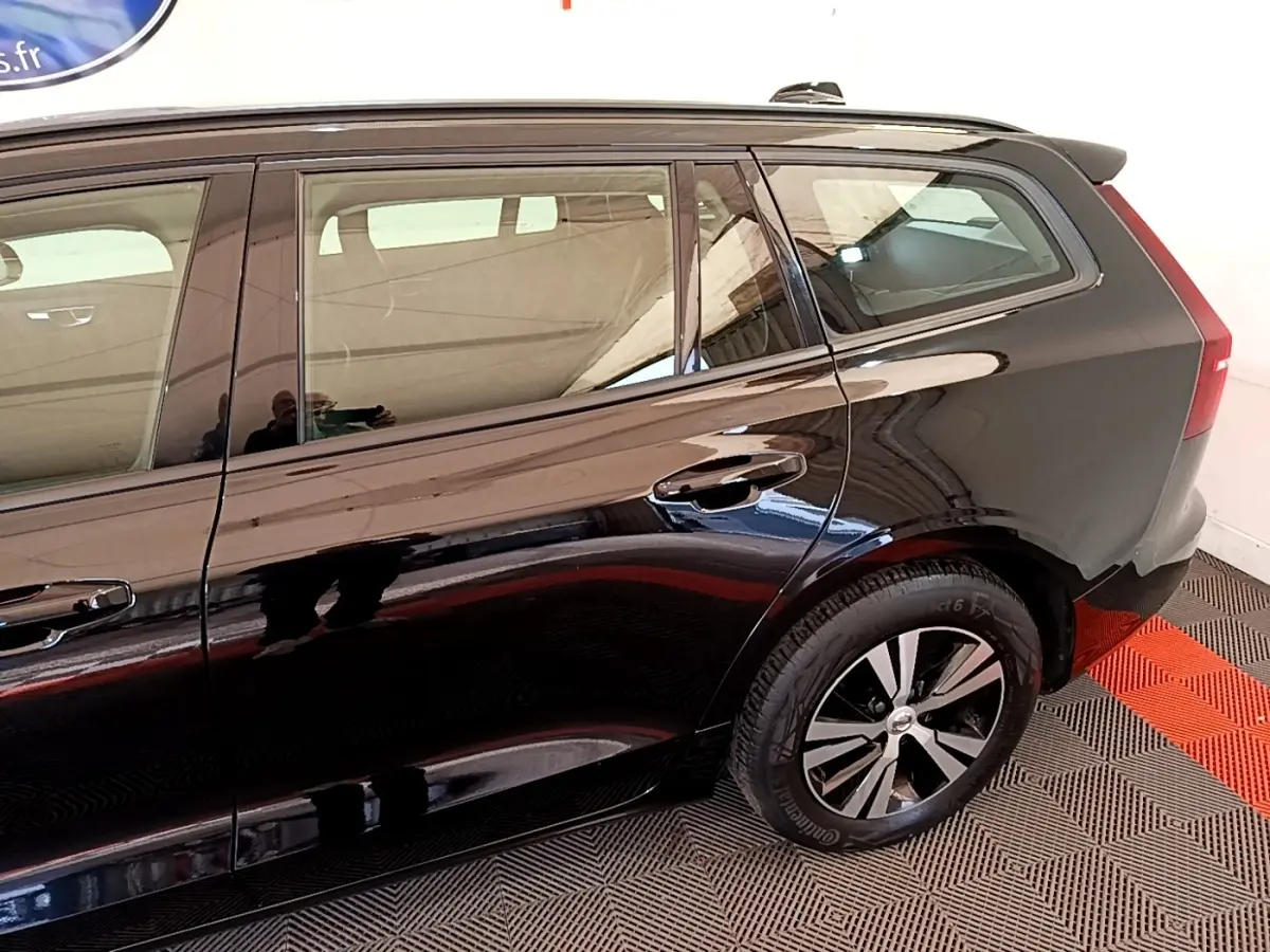 Vue latérale droite d'un Volvo V60 noir, mettant en valeur la porte arrière et la roue arrière avec jante bicolore.