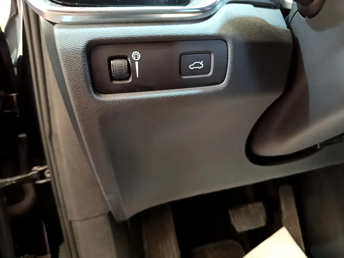 Gros plan sur commandes d'ouverture de coffre et réglage tableau de bord côté conducteur dans Volvo V60 noir 2020.