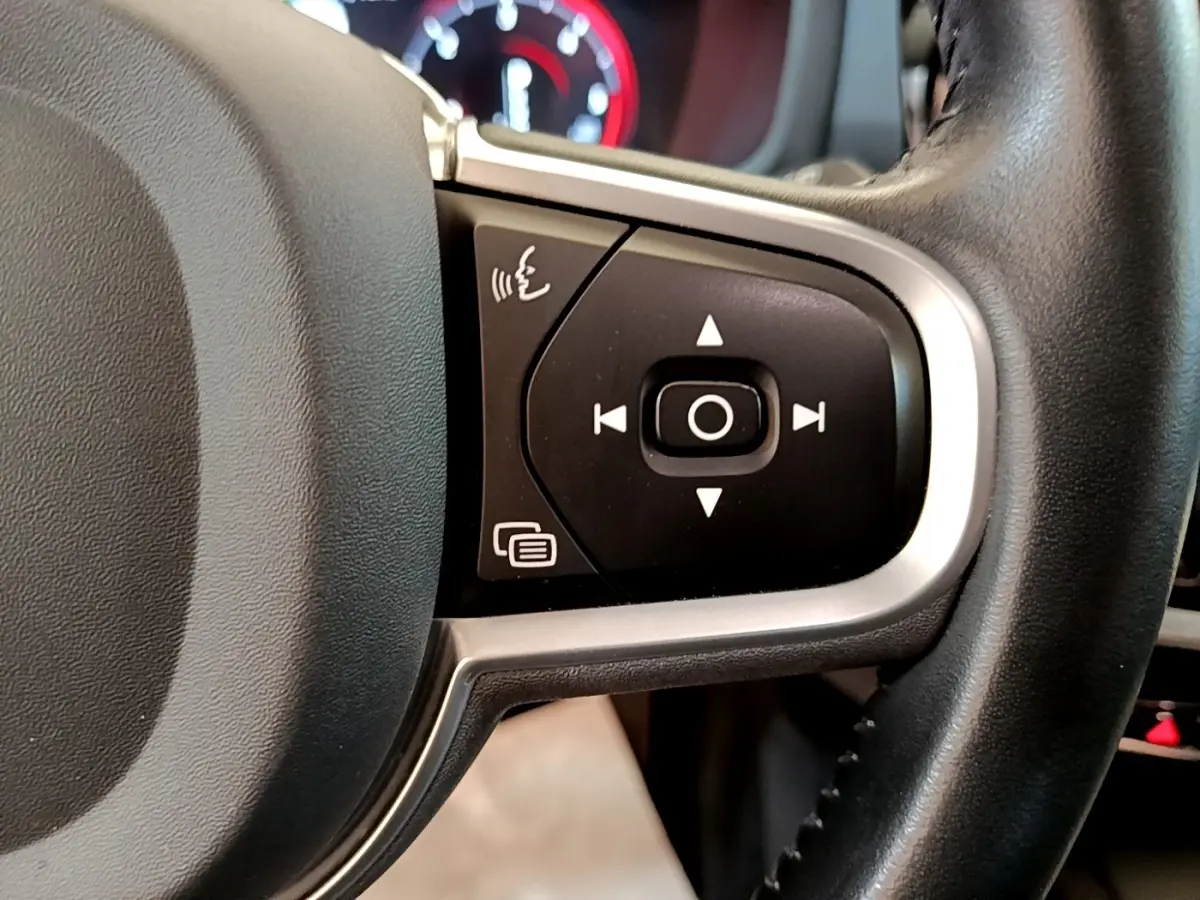 Gros plan sur les commandes multifonctions à droite du volant cuir noir d’un Volvo V60 2020, tableau de bord en arrière-plan flou.