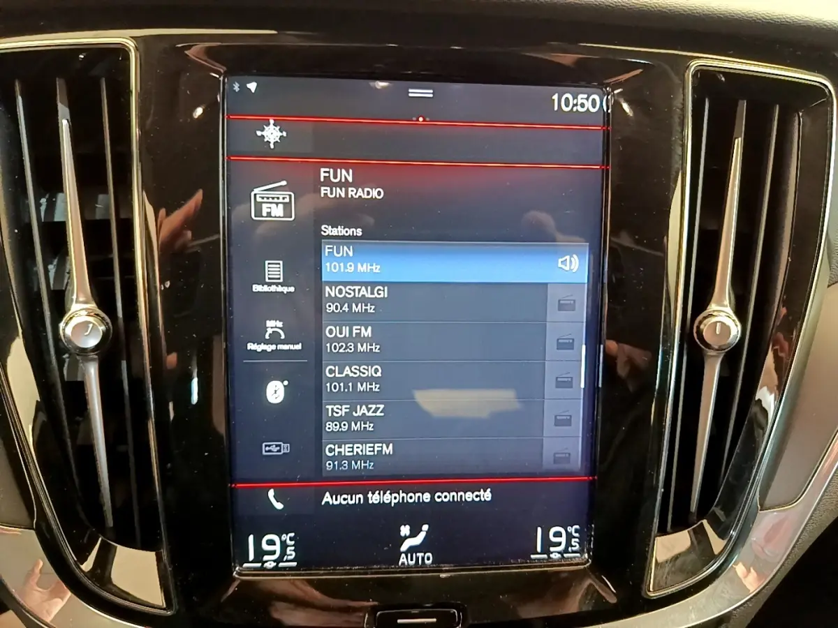 Écran tactile central de la Volvo V60 noir, affichant les stations radio avec ventilation et réglages climatisation visibles.