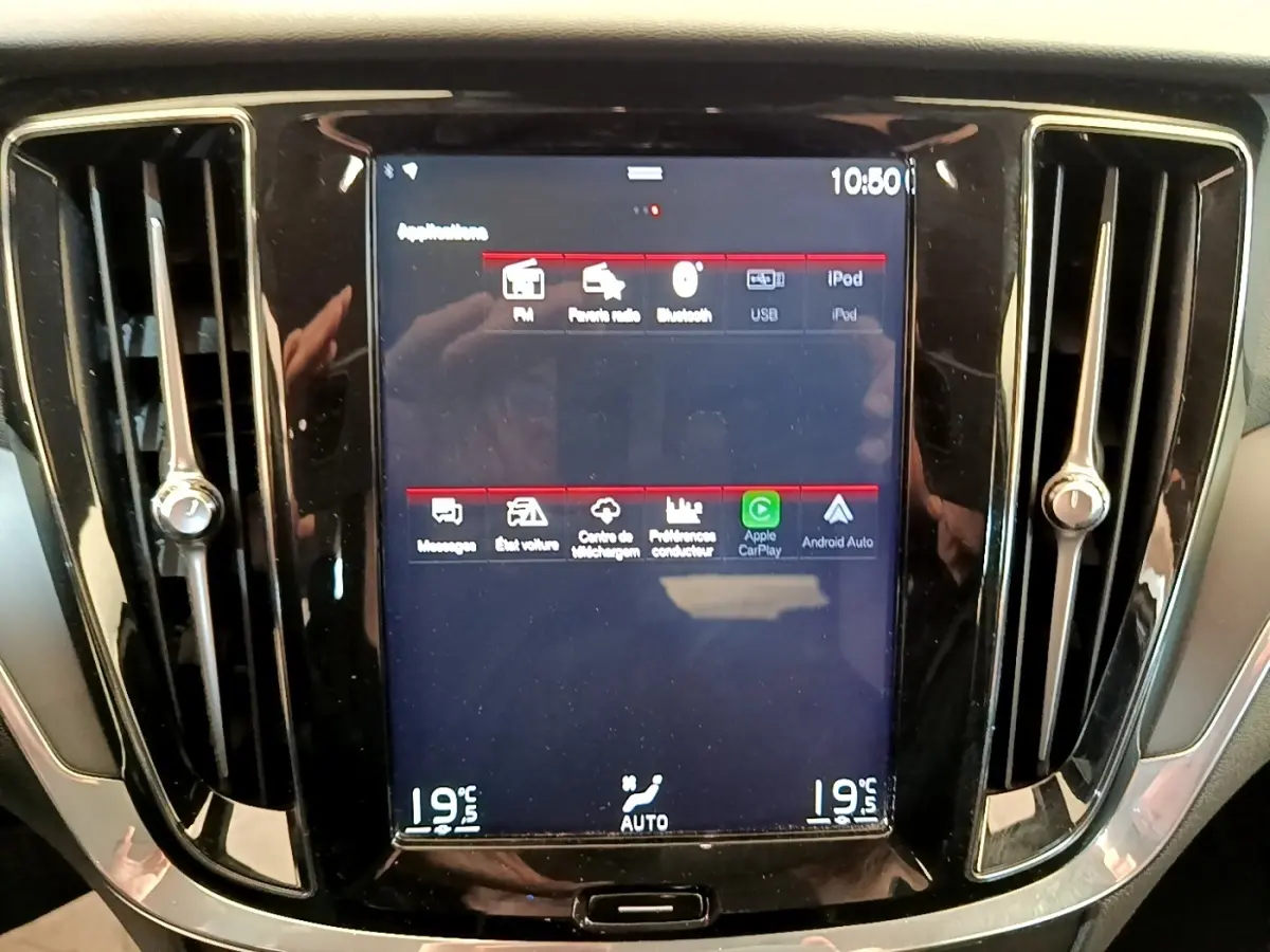 Écran tactile central allumé encadré par deux aérateurs verticaux dans l’habitacle noir d’un Volvo V60.