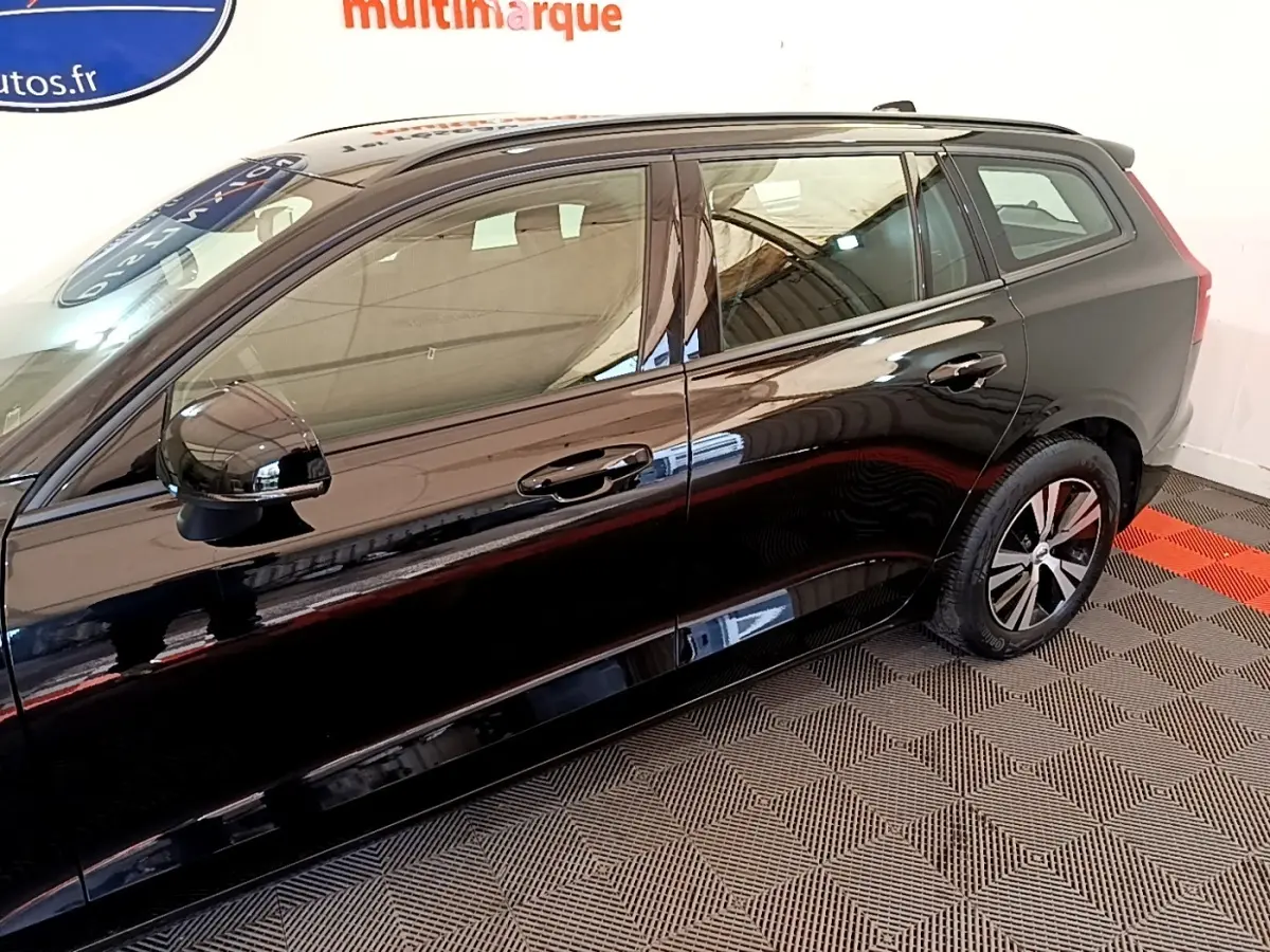 Vue de profil côté gauche d'un Volvo V60 noir brillant avec jantes alliage et rétroviseurs électriques.
