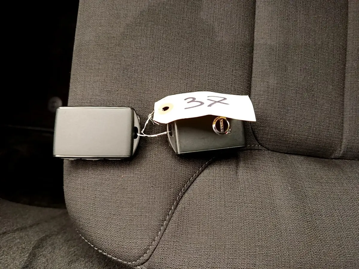 Clé de voiture Volvo V60 D3 noire posée sur un siège tissu gris foncé, vue rapprochée intérieure.