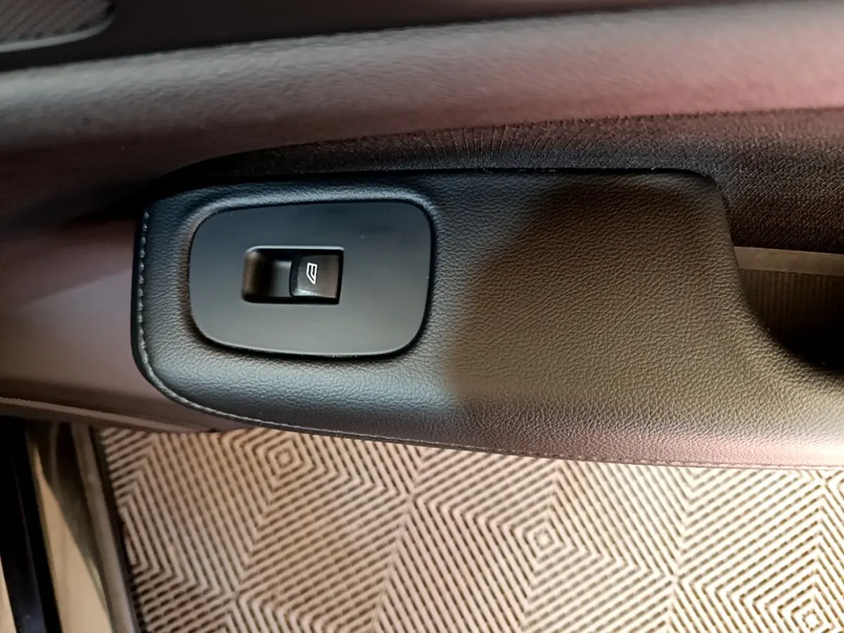 Gros plan sur le bouton de commande de la vitre électrique côté conducteur d’une Volvo V60 noire de 2020.